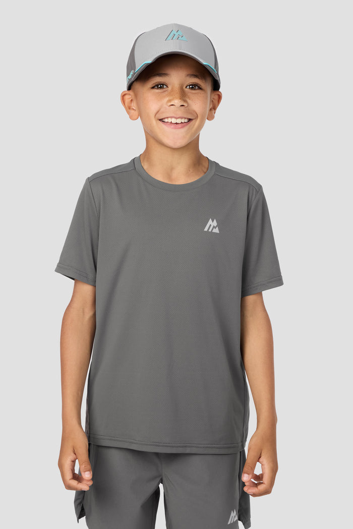 Child wearing a gray t-shirt and cap with a logo on a white background